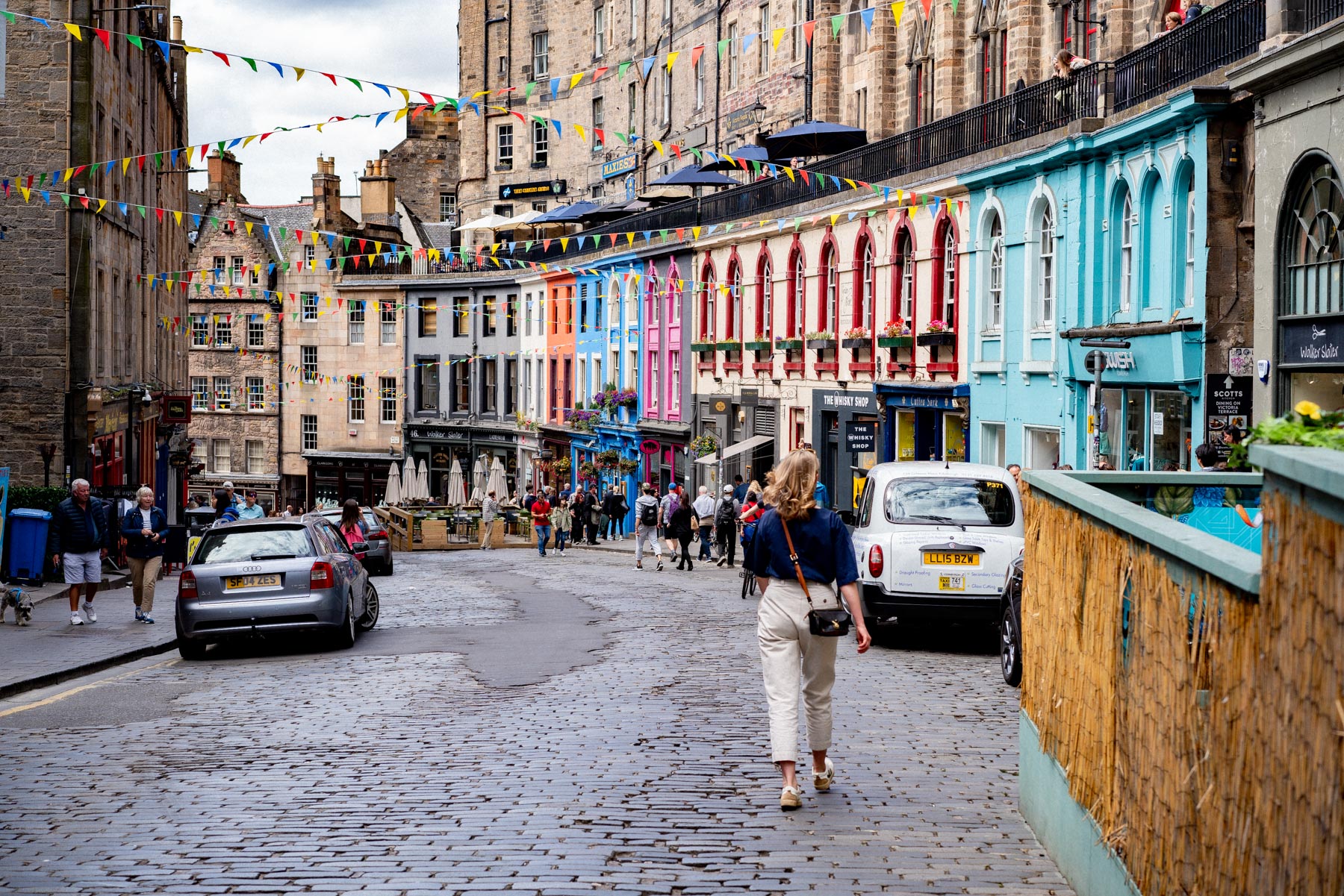 The colourful curved shopfronts of Victoria Street in Edinburgh's Old Town with bunting strung across the cobbled lane